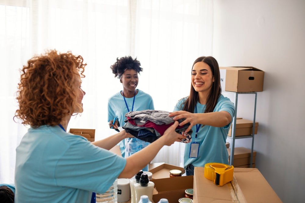 Volunteers,Collecting,Food,Donations,In,Warehouse.,Team,Of,Volunteers,Holding