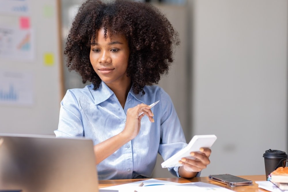 Accountant,Young,African,Businesswoman,In,Afro,Hairstyle,Using,Calculator,For