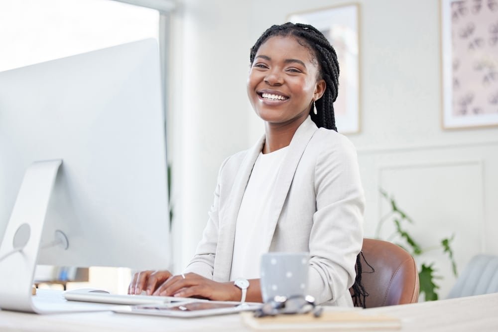 Happy,,Portrait,Of,Businesswoman,Typing,And,Computer,At,Her,Desk