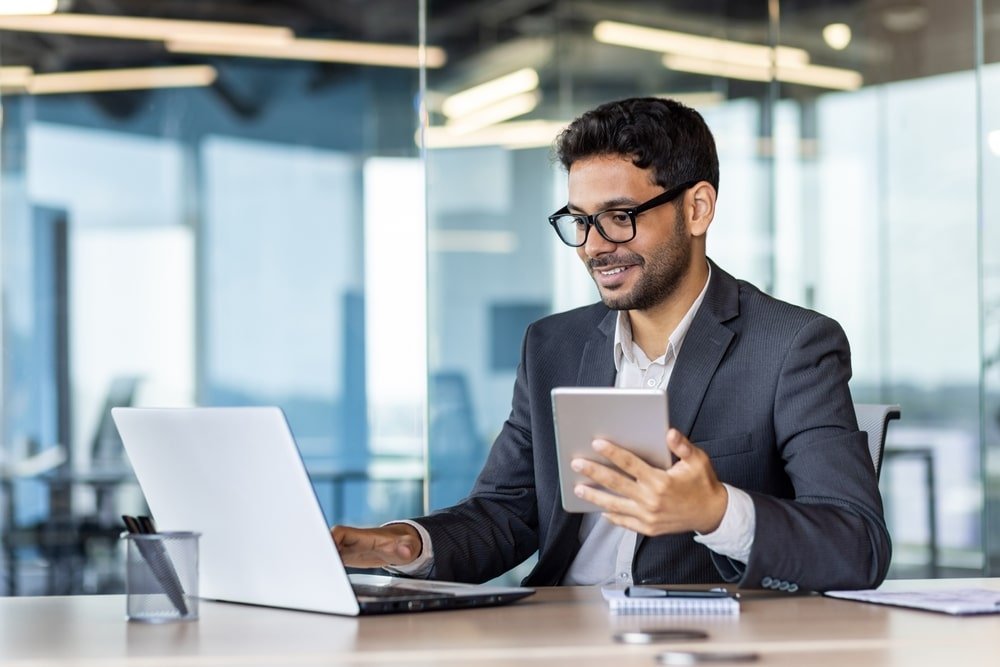 Young,Successful,Hispanic,Businessman,At,Workplace,Using,App,On,Tablet