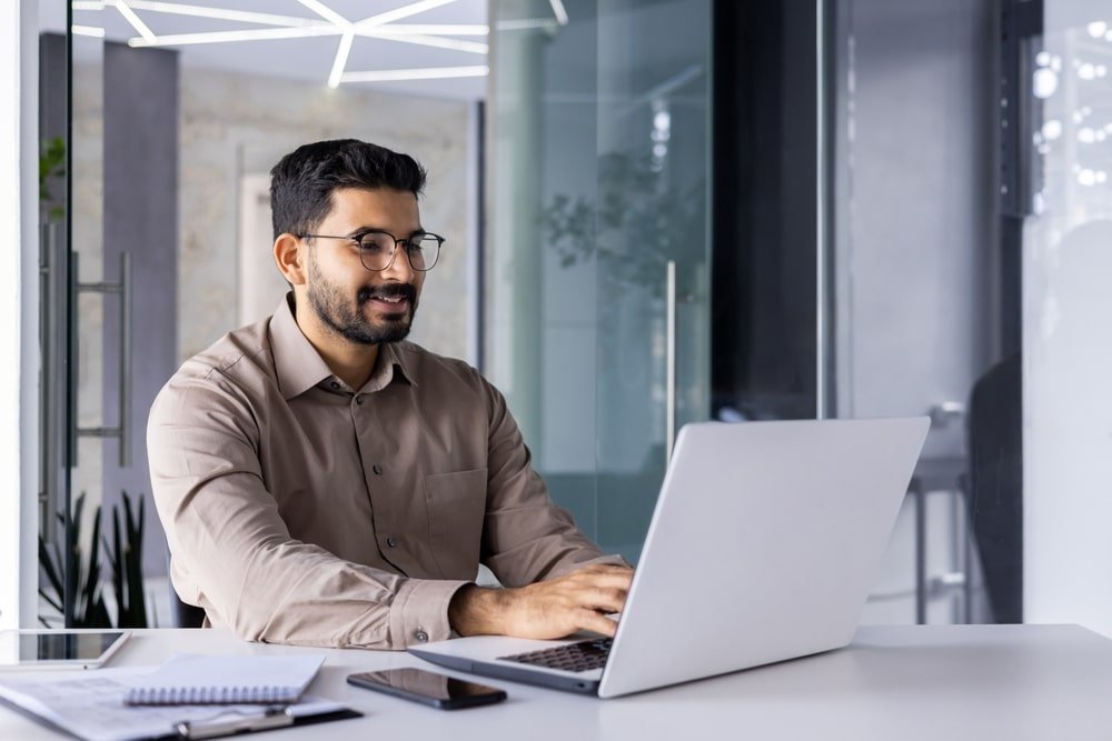 Businessman,Happy,Successful,And,Smiling,Working,With,Laptop,Inside,Office