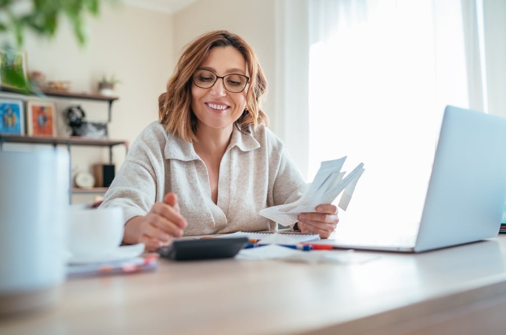 Beautiful,Middle aged,Woman,In,Glasses,And,Paper,Bills,Joyfully,Laughing